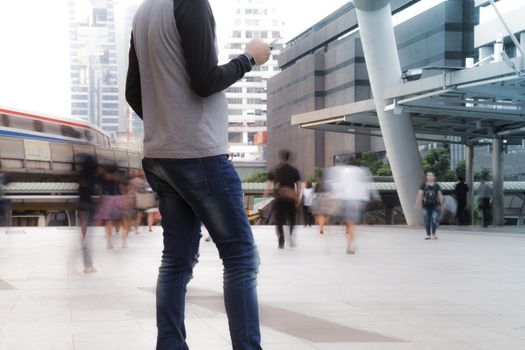 Man holding the phone with Motion Blurred People walking past