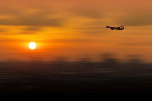 Silhouette of airplane flying in a sky over the city at sunset