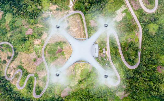 Top view of drone flying over the crooked path of road on the mountain