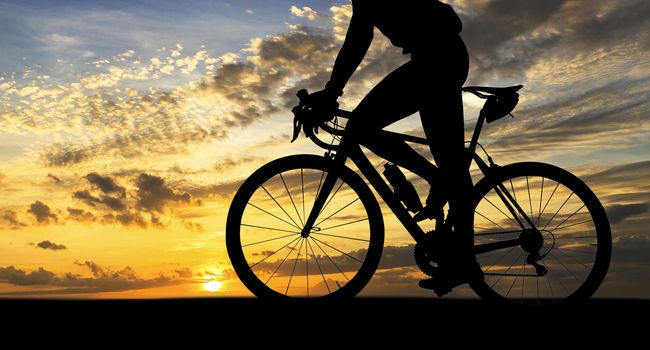 Silhouette of Man on a bicycle near the sea at sunset