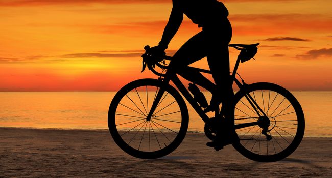 Silhouette of Man on a bicycle near the sea at sunset