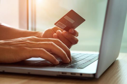 Online shopping concept. Hands holding credit card and using laptop computer.