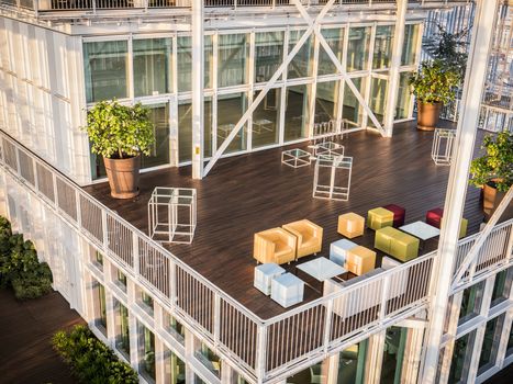 From above shot of huge glass interior building with stairs and levels and green trees growing below.