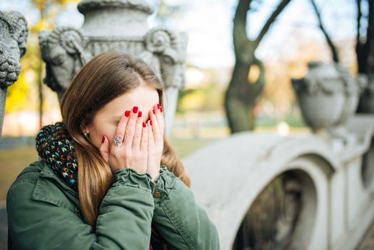 Young attractive woman with red nails covering her face with hands