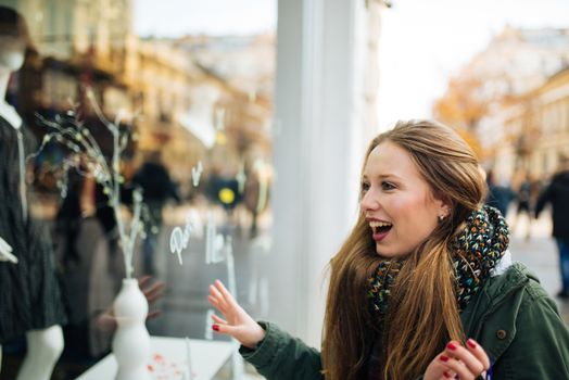 Attractive young long haired woman is excited in front of shopping window