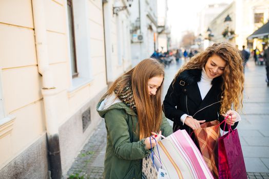 Two attractive young women is satisfied with shopping and walking down the street