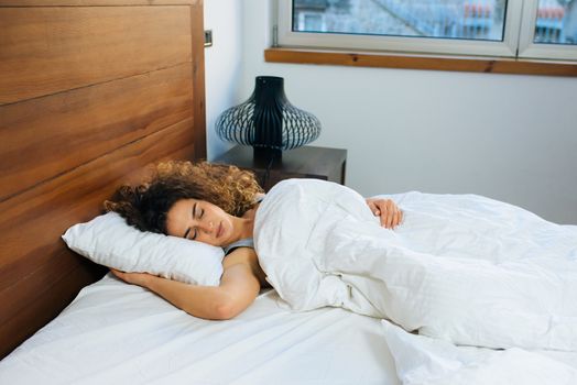 Young beautiful woman sleeping in her bed and relaxing in the morning, she is resting with eyes closed.