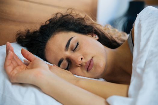 Young beautiful woman sleeping in her bed and relaxing in the morning, she is resting with eyes closed.