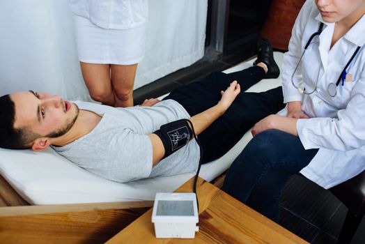 View of an caucasian nurse taking the blood pressure of a male patient