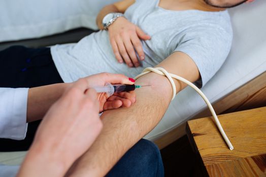 Female doctor taking a blood from male patient at the private clinic