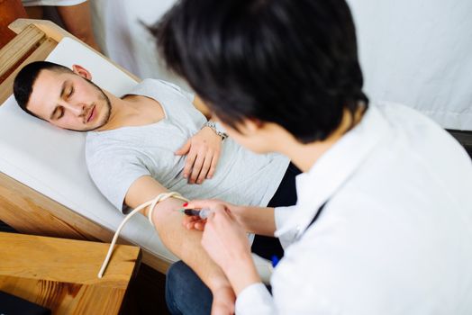 Female doctor taking a blood from male patient at the private clinic