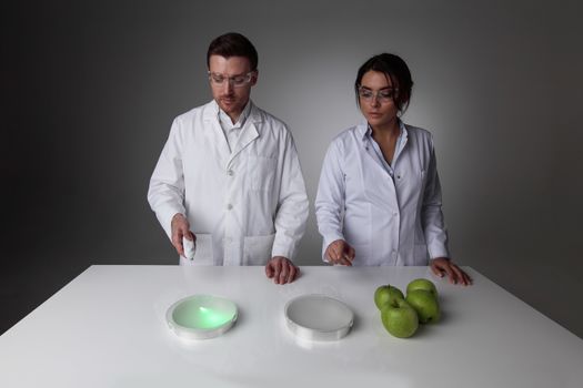 Two scientists in laboratory doing futuristic research experiments with apples, teleportation or cloning concept