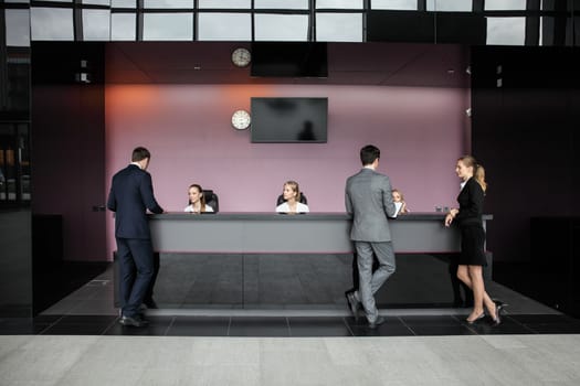 Business people at reception or front desk in office building, hotel or airport