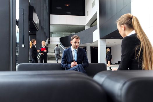 Business people talking sitting on sofa at office lobby, break, interview concept