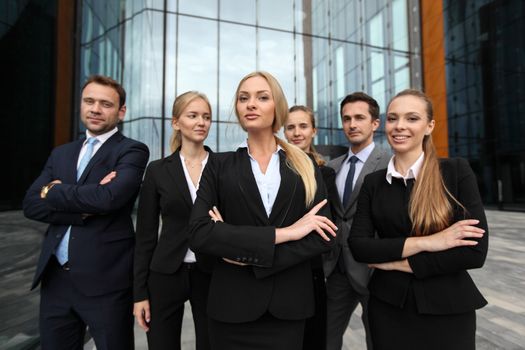 Portrait of successful business people team standing together outdoors near modern office building