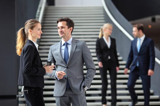 Business people standing in office lobby and talking