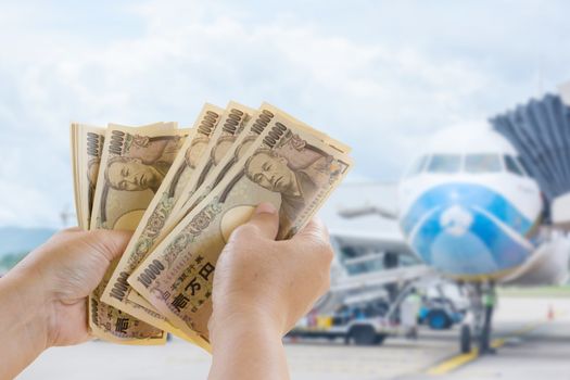 Yen Banknotes In Hand That Are Ready For Travel Tourism On Blurred Background, Tourist Business Idea