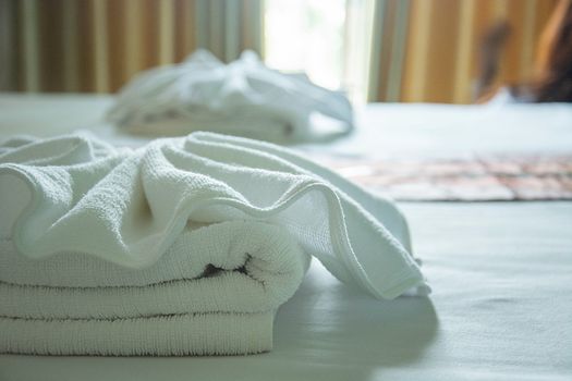 white towels on the bed with light from window.