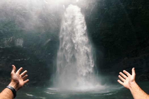 Waterfall in the rain forest. The hand points to the waterfall. Waterfall beauty of nature.