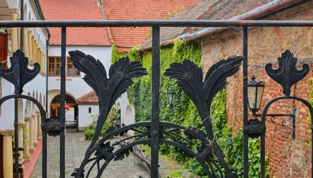 View on romantic urban scenery through forged banister. Historic urban backyard.