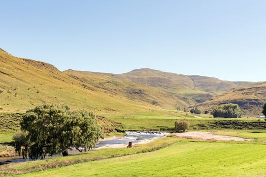 A farm landscape next to road R58 between Barkly-East and Barkly Pass in the Eastern Cape Province of South Africa. A weir in the Langkloof River is visible