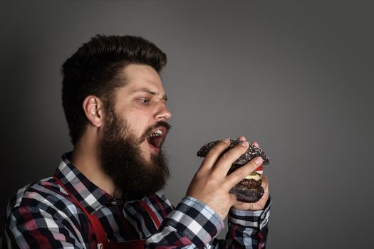 Young man biting fresh tasty black hamburger
