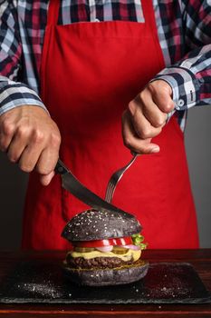 Man cuttung fresh self made black burger close up