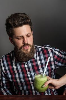 Young Man looks incredulously at woman giving him healthy eating green spinach smoothie