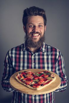 Happy smiling man holding home made heart shaped pizza