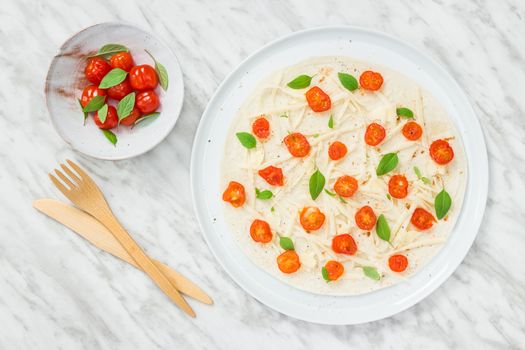 Preparing a tortilla with baby tomatoes, cheese and basil herbs.