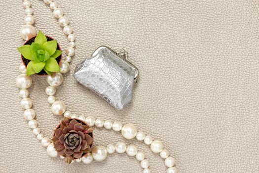 Silver purse, pearl necklace and succulent plants. Beauty and fashion composition with copy space.