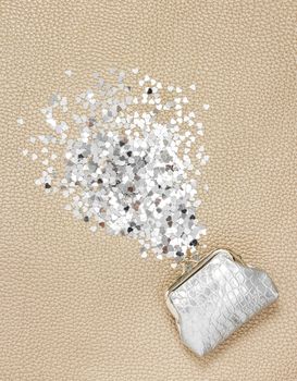 Silver purse and glitter hearts on leather background. Wealth concept.