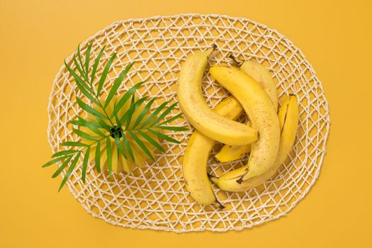 Ripe bananas and palm leaves on yellow background. Tropical summer theme.