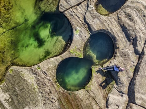 Relaxing poolside, coastal rock pools glistening in vibrant jewl-like colours on the coastal rock shelf/  Deep pools of water made by nature and enjoyed in the Autumn sunshine