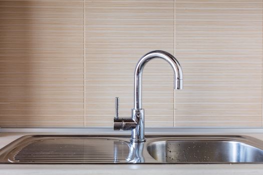 Close up of modern faucet and ceramic sink in kitchen