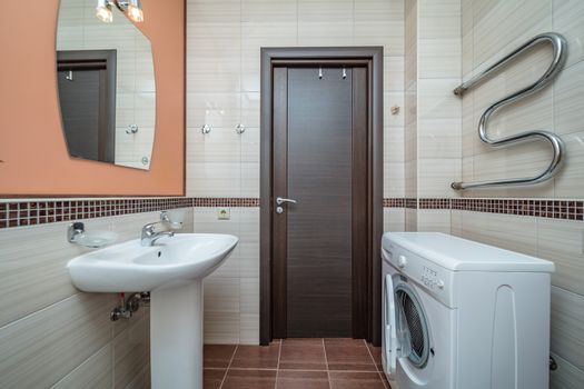 Small beige tile bathroom with bath tube sink and washing machine