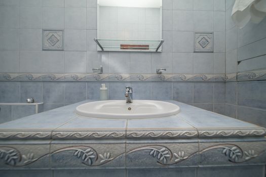 Close up of modern faucet and ceramic sink in bathroom