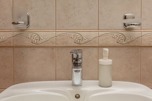 Close up of modern faucet and ceramic sink in bathroom