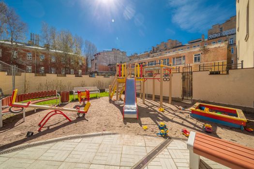 Colorful playground equipment for children in public yard in summer