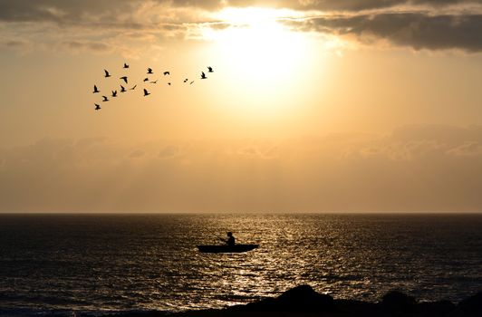Silhouette of fishermen with his boat alone in the ocean