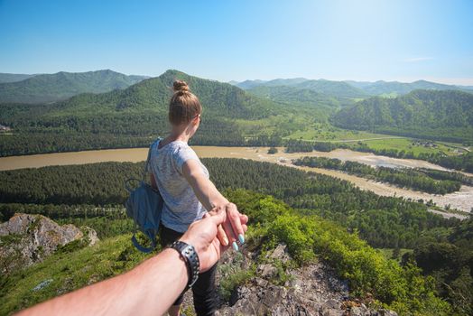 Follow me concept - Woman wanting her boyfriend to follow her in travel on the top of mountain in Altai