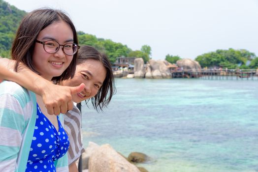 Daughter and mother is lifting thumb admire the beautiful scenery near the sea of the Koh Nang Yuan island is a famous tourist attraction in the Gulf of Thailand, Surat Thani, Thailand