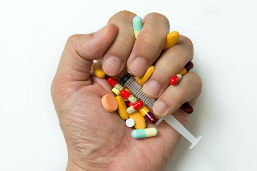 Hand full of large pile of different pills and syringe