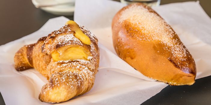 Syracuse in Sicily, Italy. Traditional fresh brioches with cream served at bar table as breackfast. Natural light, no studio.