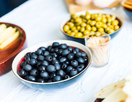 Black and green olives in bowls on white table