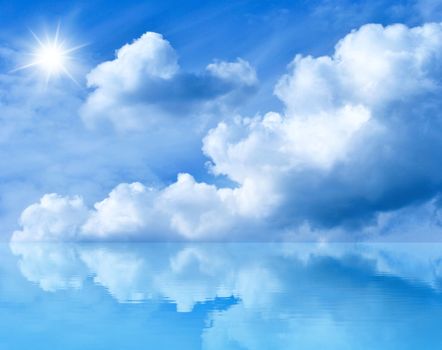 Summer background with blue sky and white clouds. Blue sunny sky above the water. Clouds and the sun are reflected in the water.                                                                                                   