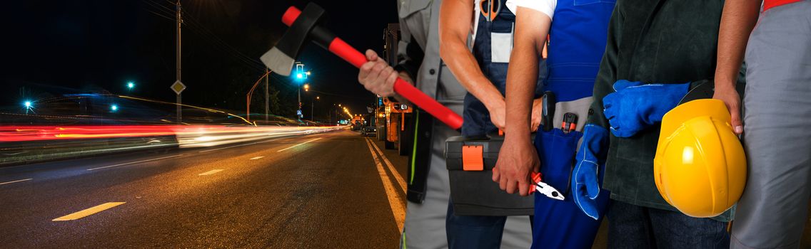 Workers on a road construction, repairing the road in the night city