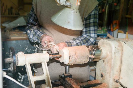 The turner begins to process the cutter with a wooden workpiece that will gradually turn from a piece of wood into an elegant vase or candlestick
