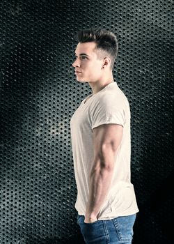 Handsome young muscular man looking to a side, in studio shot over neutral dark background