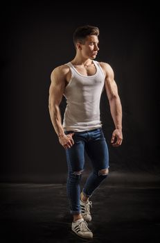 Handsome young muscular man looking to a side, in studio shot over neutral dark background